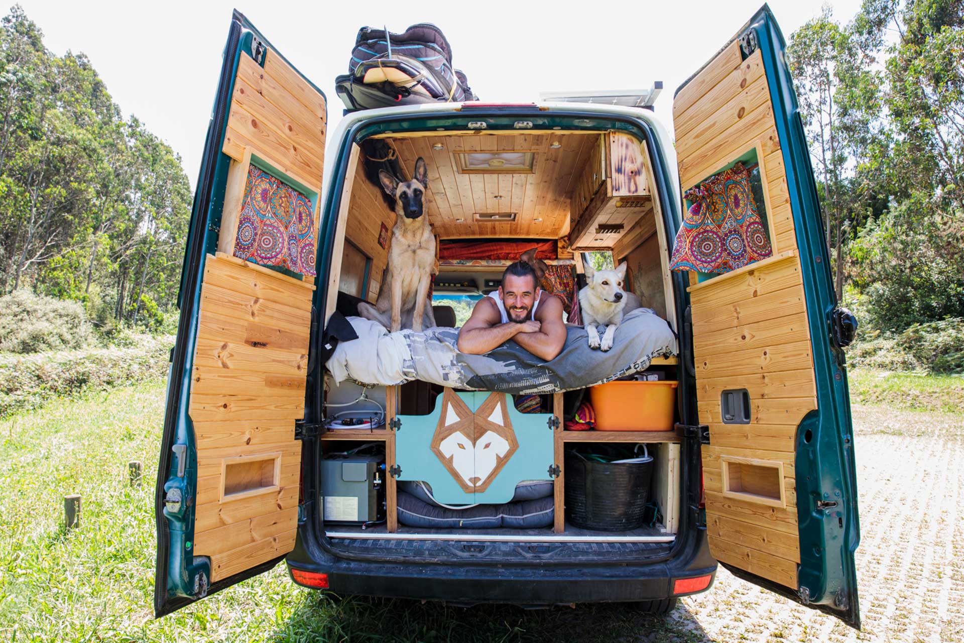 Wohnmobil DIY-Ausbau: Individuell und tierfreundlich gestaltet Selbst ausgebautes Wohnmobil mit maßgefertigtem Holzausbau, zwei Hunden und einem entspannten Besitzer, der die Flexibilität des DIY-Campers genießt.
